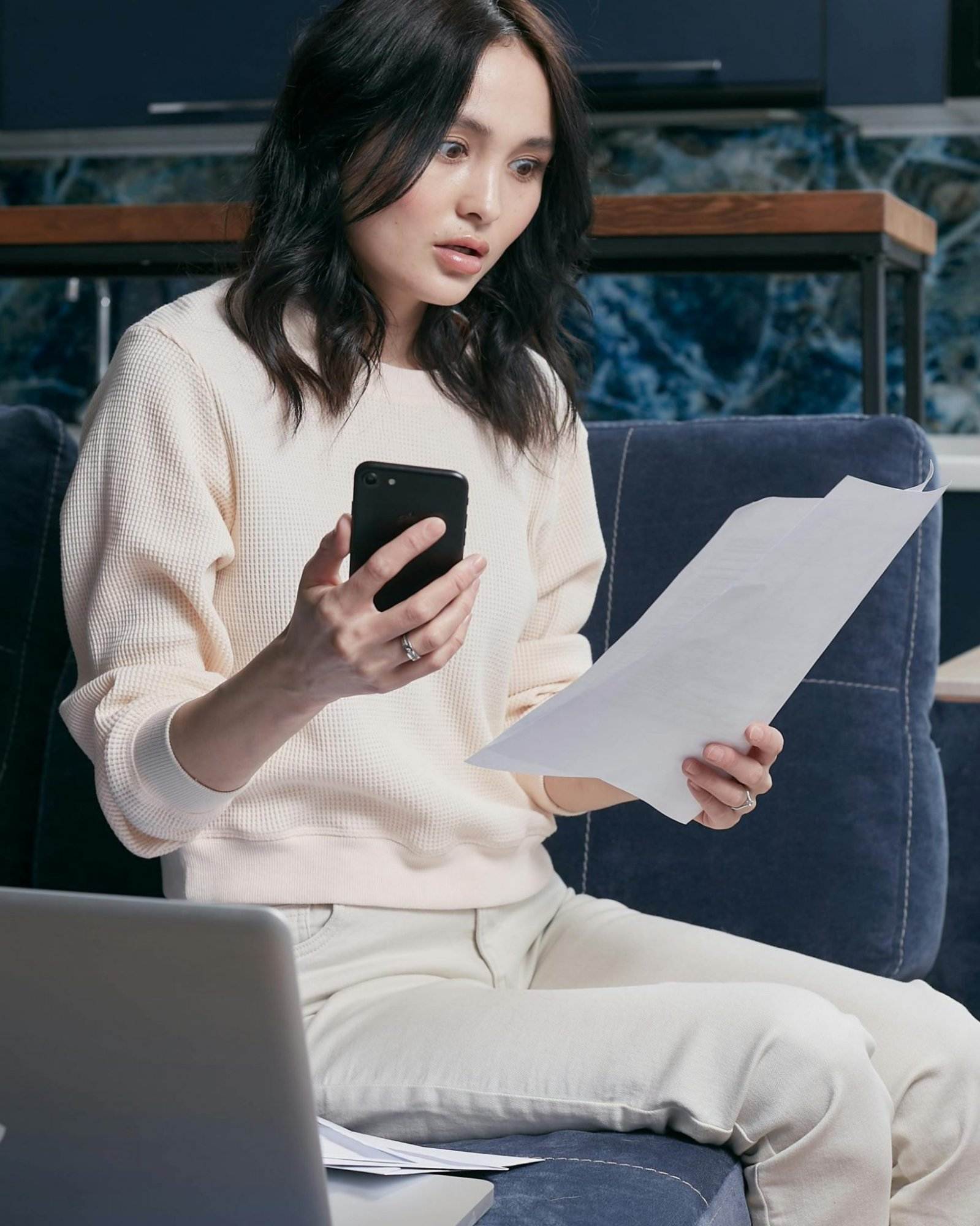 Eine junge Frau nutzt ihr Smartphone und ihren Laptop, um ihre Finanzen zu verwalten. Effektiver Rechnungseingangsprozess dank digitalisierung
